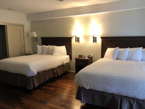 a hotel room with two beds with white sheets at Grand Eastonian Hotel & Suites in Easton