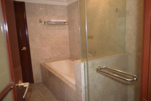 a bathroom with a shower with a tub and a sink at Grand Service Apartment @ Times Square in Kuala Lumpur