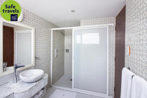 baño con lavabo y puerta de ducha acristalada en Hotel MX garibaldi en Ciudad de México