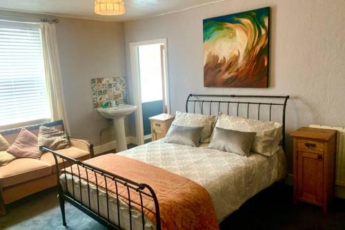 a bedroom with a bed and a couch and a sink at Stunning 18th Century 5 Bed House Old-Town Hastings in Hastings