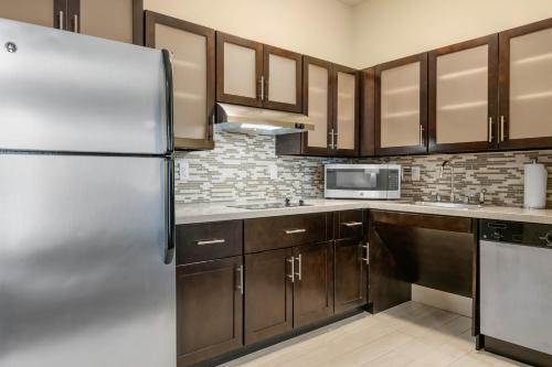 a kitchen with wooden cabinets and a refrigerator at Staybridge Suites St. Petersburg FL by IHG in St. Petersburg
