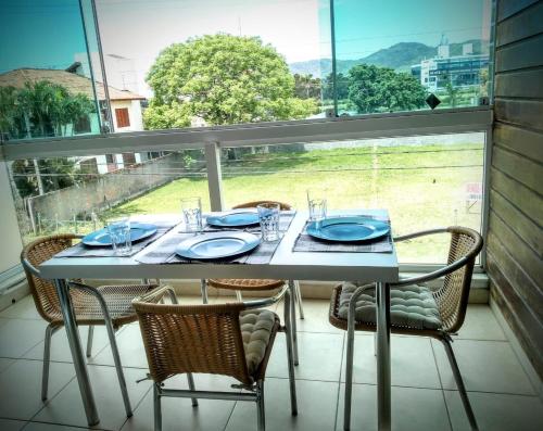 una mesa con sillas y placas azules y una ventana en Apartamento de 2 quartos a 3 minutos a pé da praia de Cachoeira de Bom Jesu com águas calmas, en Florianópolis