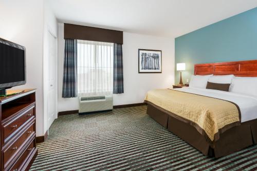 a hotel room with a bed and a flat screen tv at Baymont by Wyndham Denver International Airport in Denver