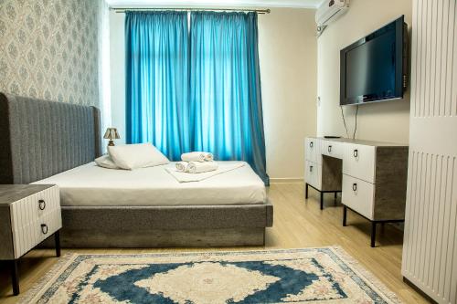 ein Hotelzimmer mit einem Bett und einem TV sowie einem Zimmer in der Unterkunft Апартаменты #89 в ЖК Zaman in Atyrau