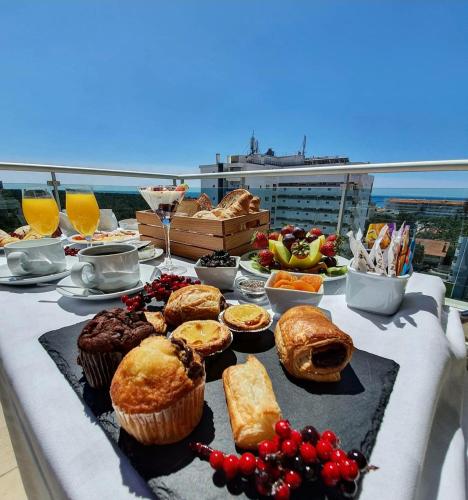 a table with muffins and other food on a balcony at Monte Gordo Hotel Apartamentos & Spa in Monte Gordo