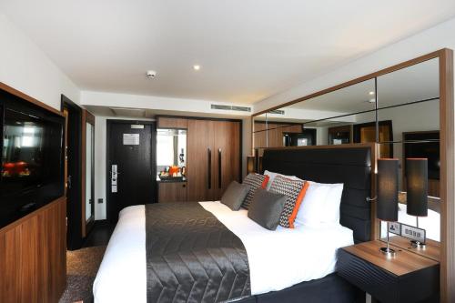 a bedroom with a large bed and a television at Crowne Plaza Gerrards Cross by IHG in Beaconsfield