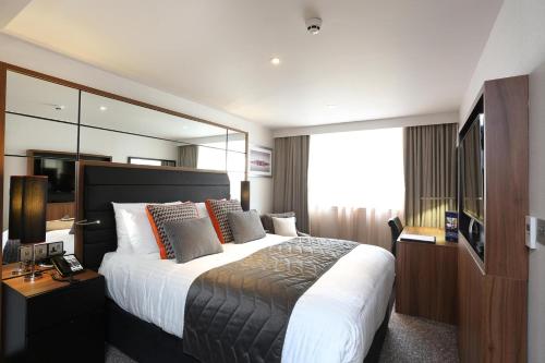 a hotel room with a large bed and a mirror at Crowne Plaza Gerrards Cross by IHG in Beaconsfield