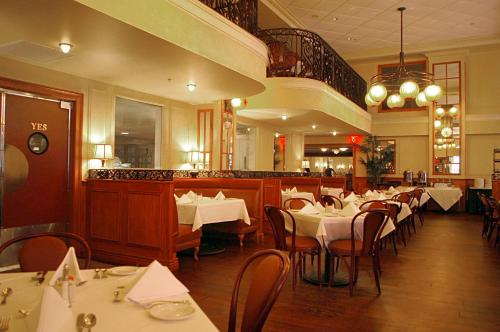 a restaurant with white tables and chairs and a staircase at Crowne Plaza New Orleans French Qtr - Astor by IHG in New Orleans