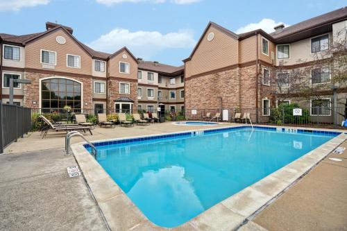 a pool with tables and chairs in front of a building at Staybridge Suites Grand Rapids-Kentwood by IHG in Grand Rapids