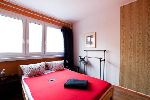 ein rotes Bett in einem Zimmer mit Fenster in der Unterkunft Park & City Alex in Berlin