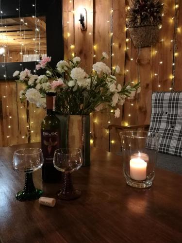 a bottle of wine and two glasses on a table with a candle at Hotel Protea Bolesławiec in Bolesławiec