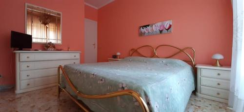 una camera da letto con pareti arancioni, un letto e una TV di Casa Giustino a Roma