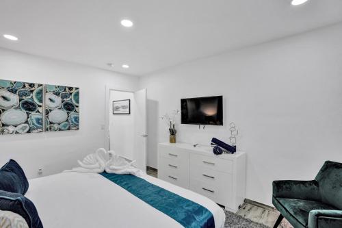 a white bedroom with a bed and a tv at Cozy studio wbeach boardwalk steps kitchen in Hollywood