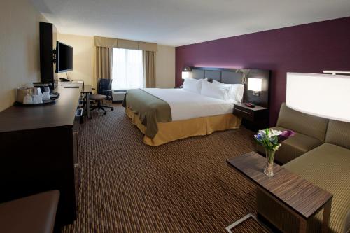 Holiday Inn Express Hotel & Suites Clearfield, an IHG Hotel في كلير فيلد: غرفة فندقية بسرير كبير واريكة
