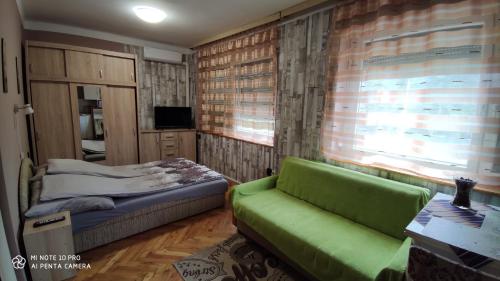 a bedroom with a couch and a bed and a window at Apartman Edit in Hark&aacute;ny