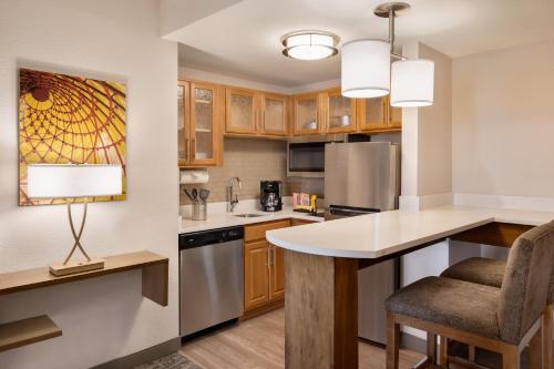 a kitchen with wooden cabinets and a table with a chair at Staybridge Suites San Antonio Downtown Convention Center by IHG in San Antonio