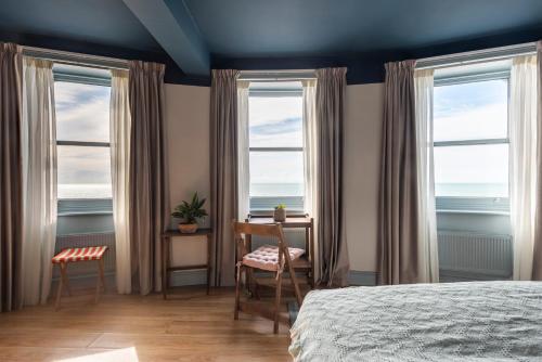 um quarto com 2 janelas, uma secretária e uma cama em Selina Brighton em Brighton & Hove