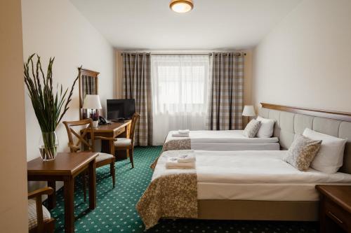 a hotel room with two beds and a desk at Hotel Ranczo Smyczyna in Smyczyna
