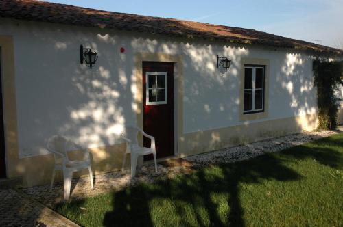 a white house with two chairs and a red door at Casa da Tia Guida in Golegã