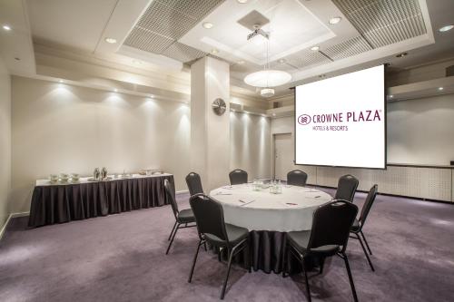a conference room with a table with chairs and a screen at Crowne Plaza Helsinki - Hesperia by IHG in Helsinki