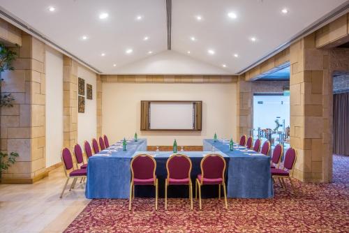 a meeting room with a blue table and pink chairs at Crowne Plaza Amman by IHG in Amman