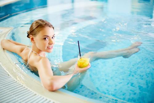 a woman in a swimming pool holding a drink at Crowne Plaza Marlow, an IHG Hotel in Marlow