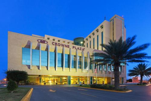 a large building with a palm tree in front of it at Crowne Plaza Torreon by IHG in Torreón