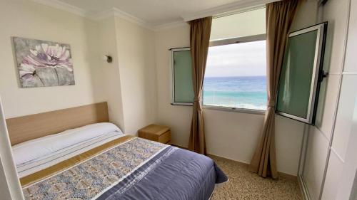 ein Schlafzimmer mit einem Bett und einem Fenster mit Blick auf das Meer in der Unterkunft Hermoso edificio Frente al mar con gran terraza y hermosas vistas in Las Palmas de Gran Canaria