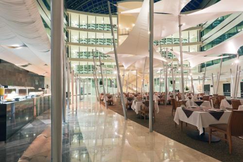a restaurant with white tables and chairs and glass walls at Crowne Plaza Leon by IHG in León
