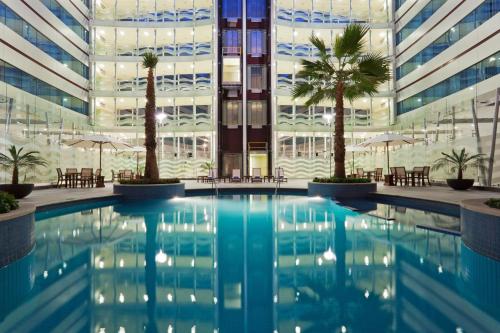 a swimming pool in front of a building with palm trees at Crowne Plaza Leon by IHG in León