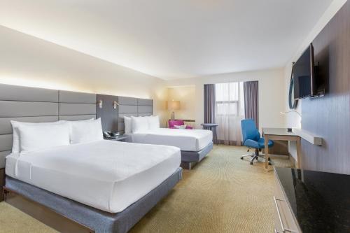 a hotel room with a large white bed and a desk at Crowne Plaza San Jose La Sabana by IHG in San José