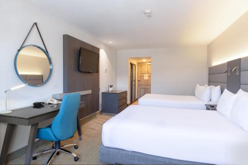 a hotel room with two beds and a desk and a mirror at Crowne Plaza San Jose La Sabana by IHG in San José