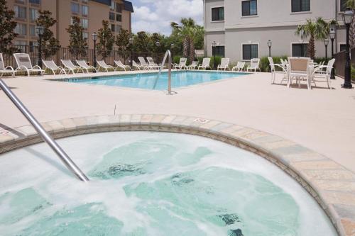 einen Whirlpool inmitten eines Pools mit Stühlen in der Unterkunft Staybridge Suites Lafayette-Airport, an IHG Hotel in Lafayette