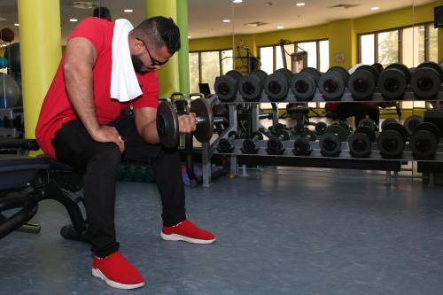 a man is sitting on a bench in a gym at Crowne Plaza Sohar by IHG in Sohar