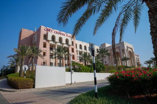 a building with palm trees in front of a street at Crowne Plaza Sohar by IHG in Sohar