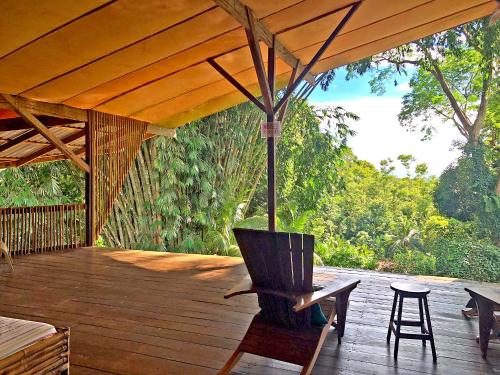 eine Holzterrasse mit einem Stuhl und einem Sonnenschirm in der Unterkunft Cascada Verde Hostel in Uvita