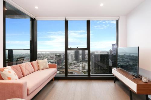 a living room with a couch and large windows at Orange Stay at Melbourne Quarter in Melbourne