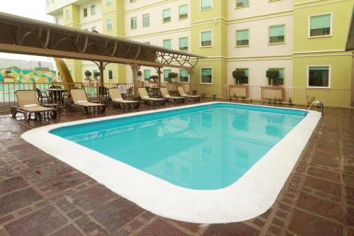 a swimming pool at a hotel with chairs and a building at Staybridge Suites Queretaro by IHG in Querétaro