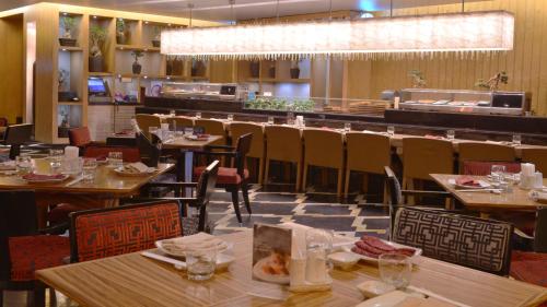 a restaurant with tables and chairs and a bar at Crowne Plaza Kuwait Al Thuraya City by IHG in Kuwait