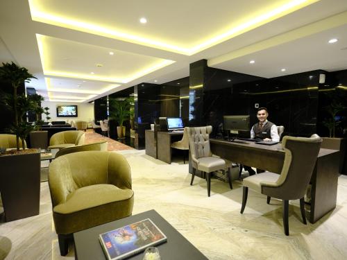 a man sitting at a desk in a hotel lobby at Crowne Plaza Kuwait Al Thuraya City by IHG in Kuwait