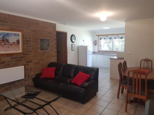 a living room with a black leather couch and a table at Grampians View Cottages and Units in Halls Gap