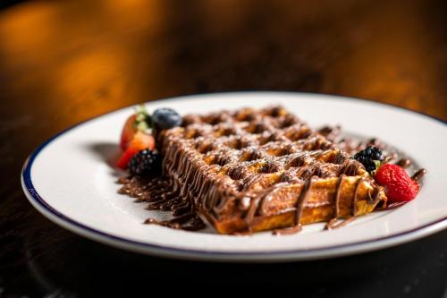 a plate of chocolate waffles and berries on a table at Crowne Plaza Muscat OCEC by IHG in Muscat