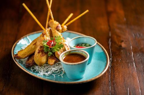 a plate of food with noodles and dipping sauce at Crowne Plaza Muscat OCEC by IHG in Muscat
