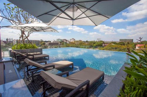 a swimming pool with chairs and an umbrella at Crowne Plaza Vientiane by IHG in Vientiane