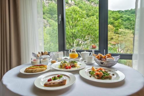 a table with plates of food on a table with a window at Crowne Plaza - Borjomi by IHG in Borjomi