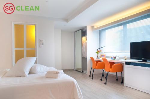 Wilby Central Serviced Apartments في سنغافورة: غرفة نوم بسرير وطاولة وكراسي