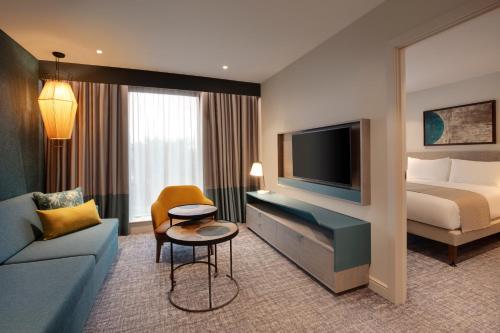 ein Hotelzimmer mit einem Bett und einem TV in der Unterkunft Staybridge Suites London Heathrow - Bath Road, an IHG Aparthotel in Hillingdon