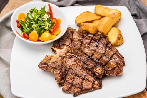 a plate with steak and potatoes and a bowl of vegetables at Crowne Plaza Barranquilla by IHG in Barranquilla