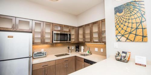 a kitchen with wooden cabinets and a white refrigerator at Staybridge Suites Houston East - Baytown by IHG in Baytown