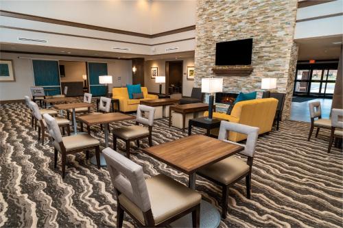 a hotel room with tables and chairs and a fireplace at Staybridge Suites - Washington DC East - Largo by IHG in Largo